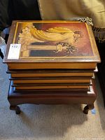 Front view of stacked book storage boxes on wooden stand with painted cover showing a woman in yellow dress holding flowers