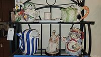 Overview of shelf containing swan teapot, two bunny teapots, figurine, and butter dish