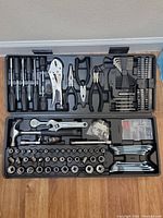 Full view of the open tool case showing the assortment of hand tools including pliers, screwdrivers, hammer, adjustable wrench, socket set, and hex keys.