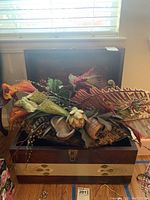 Trunk with faux flower arrangement on top, showing artificial leaves and flowers in varying shades of green, orange, and brown.