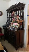 Front view of dark wood dresser with hutch mirror, showing the multiple drawers and floral decoration on top.