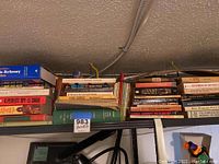 Shelf of various paperback and hardback books including crossword dictionaries, mystery and classics