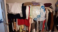 Overview of hanging clothing rack with mixed women’s garments on hangers and dry-cleaner bags