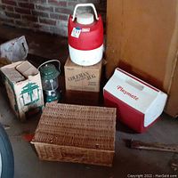 Photo of the Coleman Poly Light jug cooler, Playmate cooler, Coleman lantern in box, and wicker basket in a garage setting
