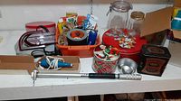 Photo showing engraving tool, travel iron, vintage mason jars, decorative tins on a shelf