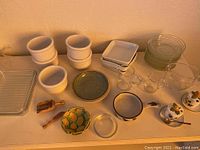 Overview of assorted glass and stone dishware including ramekins, plates, square casseroles, and decorative items