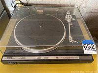 Sony black stereo turntable with clear dust cover, tonearm and controls on front panel. Label with number 652 taped on front.