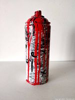 Front view of the spray can showing red paint dripping over white and black abstract markings.