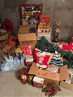 Photo shows a collection of boxed and loose Christmas decorations and garland, stockings, large pine cone, and RocMountain train set in original box.