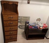 Tall narrow oak dresser and two-shelf storage unit with linens, vanity mirrors, keepsake boxes on top