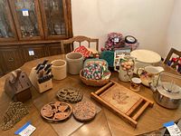 Full table view showing two wooden knife blocks, ceramic crocks, pitchers, trivets and potholders on table