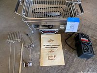 Farberware electric broiler main unit, accessories (grate, forks), and original cookbook manual laid out on concrete floor.