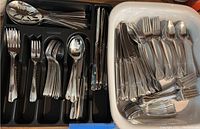 Reed & Barton and Oneida flatware sets shown in plastic trays and casserole dish with organized forks, knives, spoons and serving utensils.