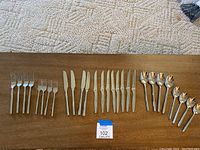 Full assortment of flatware arranged on wooden surface showing forks, knives, and spoons.