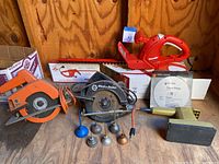 Photo showing two Black & Decker circular saws (orange and black) with cords, along with a vintage sander and small oil cans in front.