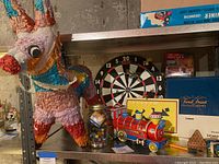 Overall lot showing colorful donkey piñata, dartboard, toy train, jar of marbles