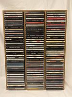 Full front view of wooden CD stand loaded with 120 CDs, showing three columns and visible CD titles.