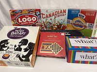 Photo showing the seven boxed board games grouped together with titles clearly visible.