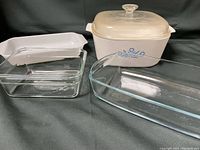Four casserole dishes: Large white Corningware covered casserole with blue pattern, three transparent glass casseroles of varying sizes.