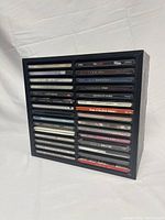 Front view showing all 30 CDs arranged horizontally in the pressboard wood stand's slots in two vertical columns.