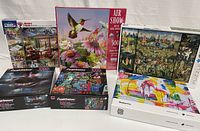 Photo showing six puzzle boxes including the two sealed, variety of styles and piece counts.