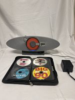 Front view of Sony personal audio system showing circular orange and red CD loader, speaker grill, and power adapter with USB cord connected.