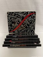 Four stacked journals with titles Twilight, New Moon, Eclipse, and Breaking Dawn with a decorative tin box behind them.