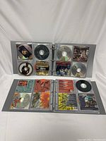 Open view of one binder showing two pages of clear CD sleeves with multiple CDs inserted with visible CD labels and artwork.