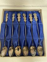 Close view of spoon handles showing detailed Asian coin motifs and pattern, slight tarnish visible