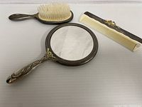 Full set viewed from above including mirror, brush, and comb arranged on flat white surface