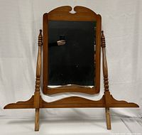 Full view of the vintage cheval mirror showing wooden frame, arched top and spindle side supports.