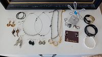 Top-down view of all jewelry items including bracelets, rings, necklaces, earrings, and ring holder arranged neatly.
