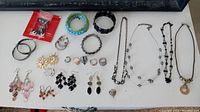 Full assortment of jewelry including bracelets, necklaces, rings, and earrings arranged on a table surface.