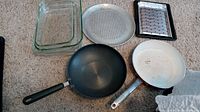 Full lot overview showing Pyrex baking dishes, pizza pan, small rack, Circulon wok, and Bialetti pan.