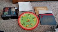 Full lot with 6 cutting boards including bamboo and plastic types, white serving dish with scratches, orange and green round serving platter, and boxed Mr. Coffee mugs with stirrers.