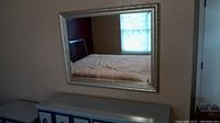 Full view of the large rectangular mirror mounted on a wall above furniture showing its size and reflective quality.