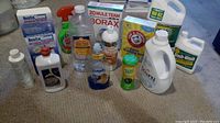 A wide view showing various household cleaning products including Borax, washing soda, fabric softener, dish soap, and more
