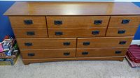 Front view of large wood dresser showing black recessed drawer handles and multiple drawer sizes.