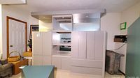 Large light-colored media and display cabinet with mirrored and lighted top section in a residential room.