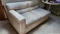 Photo of single sofa sectional piece with armrest and back cushions showing striped upholstery fabric and wear marks.