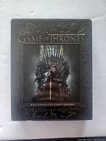 Front cover of Game of Thrones The Complete First Season Blu-ray box set showing Ned Stark on the Iron Throne.