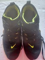 Top view of black Nike golf shoes showing neon yellow inner lining and Nike logo on toes.