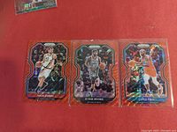 Front of three Panini Prizm basketball cards featuring Ivica Zubac, Kyrie Irving, Chris Paul on red background.