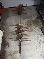 Large wooden furniture clamp approximately 6 feet in length with metal hardware and wooden handles lying on concrete floor.