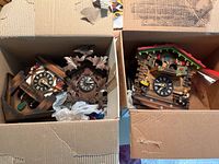 Top view showing two boxes each containing one or two traditional cuckoo clocks with carved wooden and chalet styles visible.