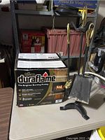 Box of Duraflame Gold firelogs and metal fireplace tools visible on table