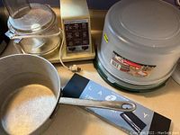Photo showing Hamilton Beach food processor, aluminum cooking pot, Rubbermaid cake keepers, and carving set case