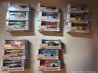 Top-down view of the 16 Racing Collectables boxed cars arranged in five groups, showing car models and numbers visible on packaging.