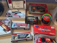 Overview of assorted racing collectibles including diecast cars in original boxes and colorful collectibles