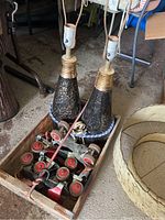 Photo showing two vintage lamps with blue-speckled bases, electrical cords, a wooden Pepsi crate, and three pairs of shoe skates inside the crate.